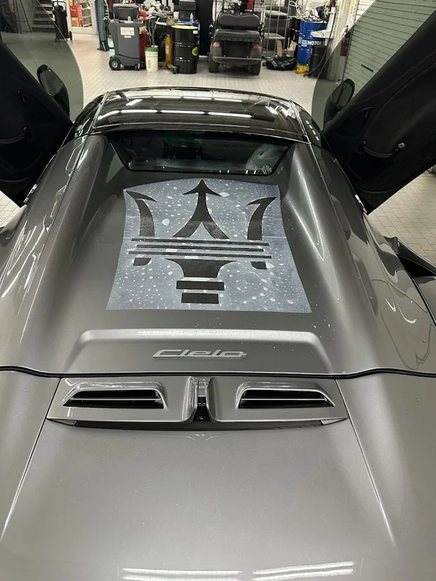 The rear deck of a silver Maserati MC20 Cielo, the trident visible through the glass