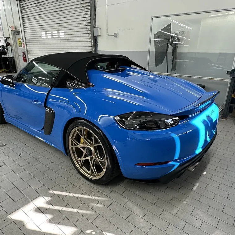 A blue Porsche 718 Spyder RS with gold wheels