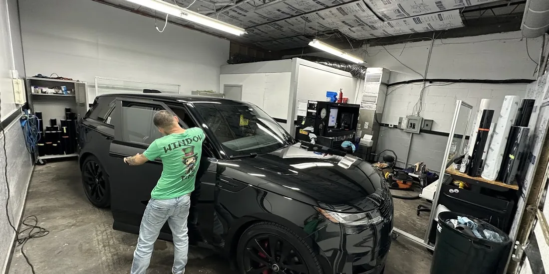 A Murphys fitter applying film to the rear window of a black car